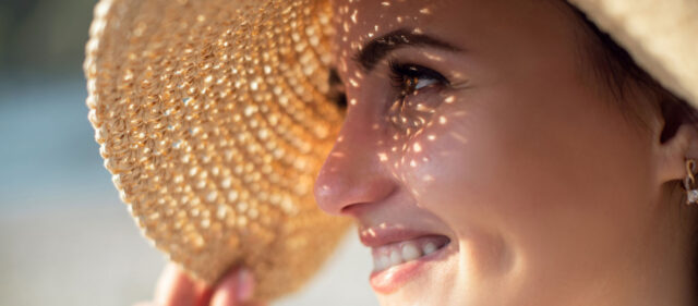a woman blocking out the sun by wearing a hat